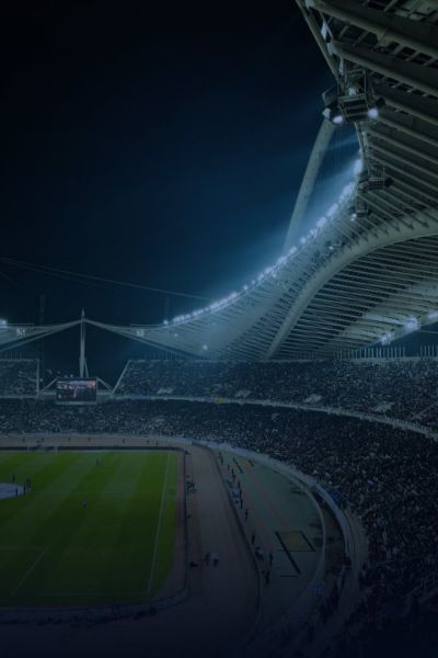 Floodlit football stadium filled with spectators at night